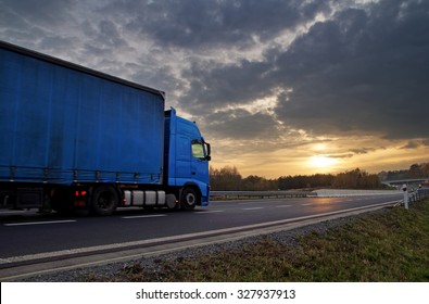 Blue Truck On Highway At Sunset In The Countryside. Dark Clouds In The Sky.