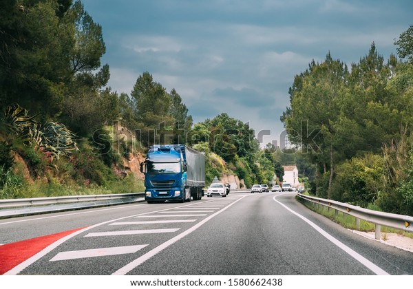 Blue Truck Or\
Traction Unit In Motion On Road, Freeway. Asphalt Motorway Highway\
Against Background Of Forest Landscape. Business Transportation And\
Trucking Industry
