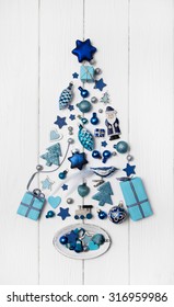 Blue and turquoise christmas tree of small miniatures on white wooden background for decoration.