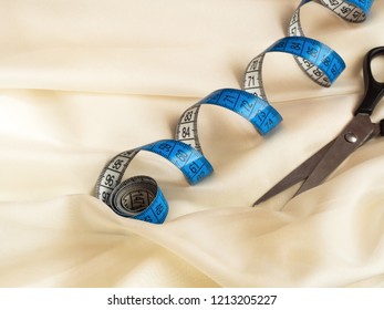 Blue Twisted Tape Measure And Scissors On Cream Tulle, Macro Shot, Sewing Concept