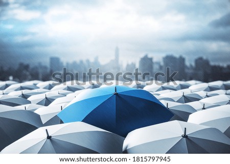 Blue umbrella on top of other gray umbrellas on city background. Business and safety concept