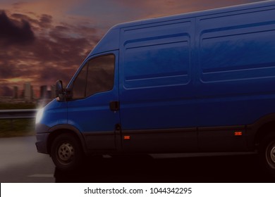 Blue Van With Driving Fast On The Countryside Road Against Night Sky With Sunset