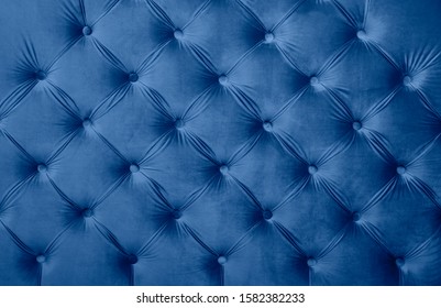 Blue velvet capitone textile background, classic retro Chesterfield style checkered soft tufted fabric furniture diamond pattern decoration with buttons, close up