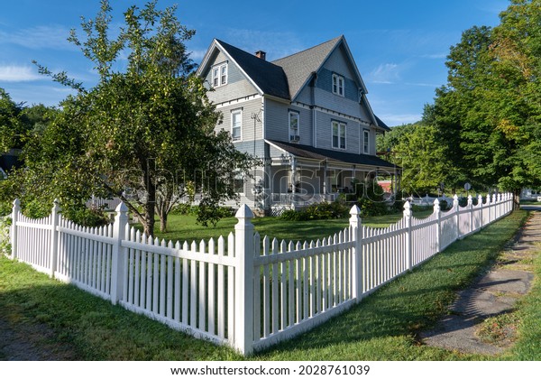 Blue Victorian mansion, inn\
in rural Pennsylvania, neatly restored with white picket fence blue\
sky