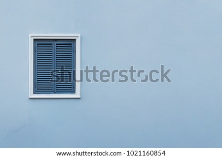 Blue wall of the house with a closed window left and details.