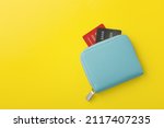 Blue wallet with credit card on yellow background, flat lay with copy space