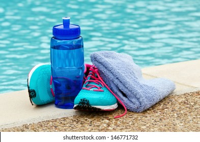 Blue Water Bottle With Running Shoes And Towel By Pool. Exercise And Hydration Concept. Copy Space.