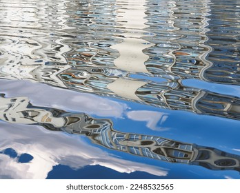 Blue water reflex background. Abstract reflection and abstract inspection elements in water. City, buildings, house elements distorted in the river. Rippled water texture. Disordered clouds surface.  - Powered by Shutterstock