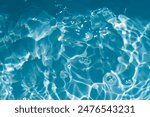 Blue water with ripples on the surface. Defocus blurred transparent blue colored clear calm water surface texture with splashes and bubbles. Water waves with shining pattern texture background.