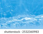 Blue water with ripples on the surface. Defocus blurred transparent blue colored clear calm water surface texture with splashes and bubbles. Water waves with shining pattern texture background.