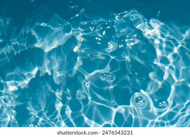 Blue water with ripples on the surface. Defocus blurred transparent blue colored clear calm water surface texture with splashes and bubbles. Water waves with shining pattern texture background.