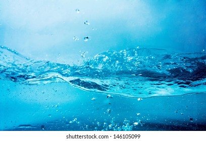 Blue water splash and droplet in the air drop into moving water. Bubbles in wave and rough surface  with swirl. - Shutterstock ID 146105099