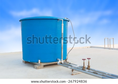 Blue water tank of industrial building on roof top or deck and blue cloud sky background