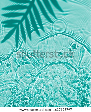 Blue water texture background on the noon sunlight with tropical leaves shadow. 
