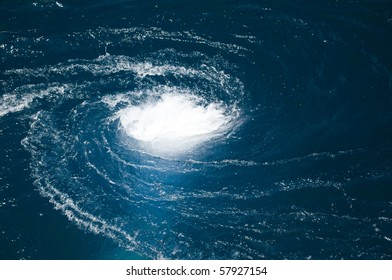 A blue water vortex that funnels below the surface.