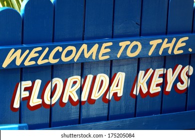 Blue welcome to the Florida Keys sign painted on picket fence
