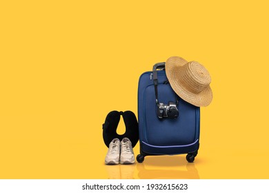 Blue Wheeled Hand Luggage And Essential Travel Items Against Yellow Background.