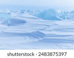 Blue and white abstract natural textured background of snowy ice surface of Baikal Lake on frosty winter day. View of layered structure of snow crust on ice field of frozen lake. Copy space, mock up