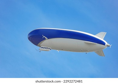 A blue and white airship with passengers on board flies against the blue sky. 