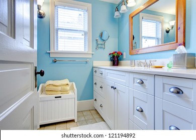 Blue And White Bathroom With Lots Of Storage Space With Open Door.