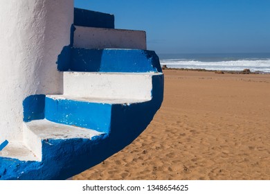 Blue And White Color Of A Lifeguard Tower, Detail Of The Stairs. Golden Clean Sand Of The Beach. Empty Beach In The Autumn. Horizon Of The Atlantic Ocean. Blue Sky. Beddouza Beach, Morocco.