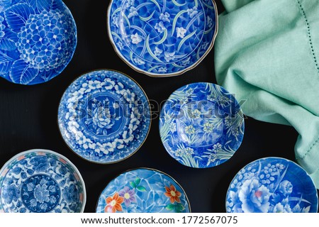 Blue and white decorative Japanese ceramic plates on black background - Top view photo