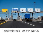 Blue and white lorry with empty body, crosses the motorway tollgate. 