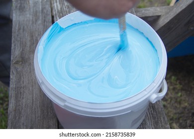 Blue And White Paint Were Mixed In A Bucket. Stir With A Stick