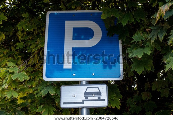 A\
blue and white parking sign with a tree in the background in\
Csillaghegy, Budapest, Hungary on a sunny autumn\
day.