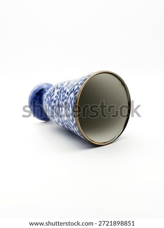 A blue and white patterned ceramic vase lying on its side against a clean white background, showcasing delicate floral motifs and a glossy finish.