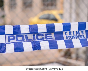 Blue And White Police Tape Cordoning Off A  Crime Scene Area With A Yellow Car At A Industrial Area, Australia 2016
