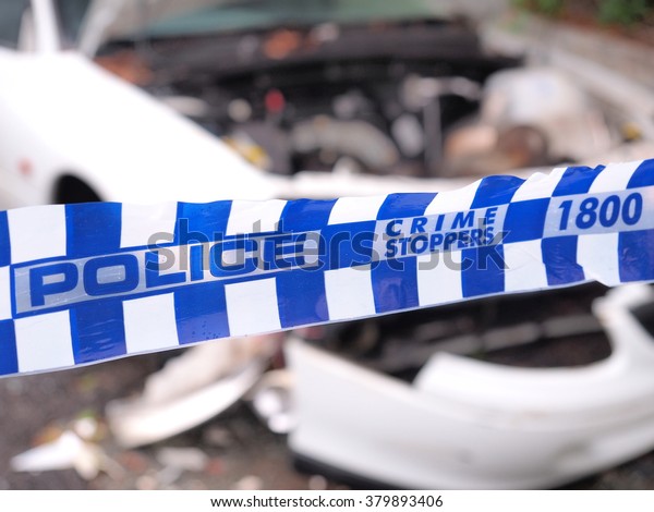 Blue\
and white Police tape cordoning off a  crime scene area with a\
badly accident damaged white car, Australia\
2016\

