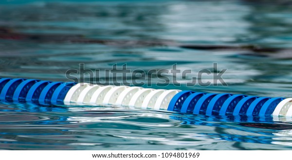 Blue and white pool lane divider with ripples\
in foreground and\
background