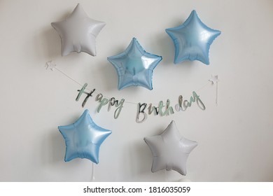 Blue And White Star Balloons And The Inscription Happy Birthday On The White Wall. Birthday Decor