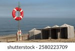 Blue and white striped beach tents at Suave Mar Beach. Lifebuoy on the pole. Lifeguard lookout post, with big red lifebuoy, Esposende, Portugal. The Litoral de Esposende Protected Landscape.