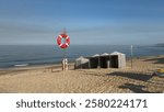 Blue and white striped beach tents at Suave Mar Beach. Lifebuoy on the pole. Lifeguard lookout post, with big red lifebuoy, Esposende, Portugal. The Litoral de Esposende Protected Landscape.