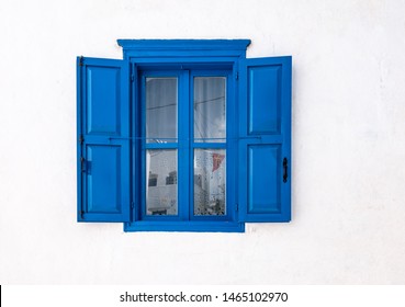 Blue window with open shutters and white wall of greek house in Amorgos, Greece.