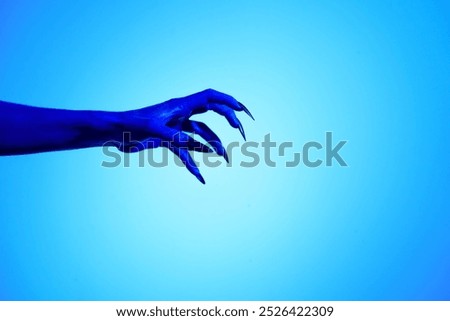 A blue witch hand with sharp red nails, set against a backdrop of blue fire. This eerie figure embodies demonic, ghostly, and zombie elements, perfect for Halloween horror and fantasy settings.