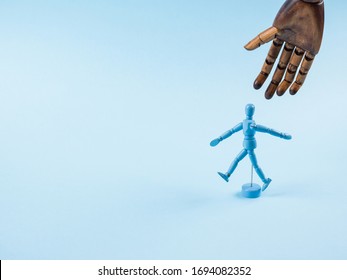 Blue wooden human marionette dummy walking alone on monochrome backdrop with big wooden about to take him. - Powered by Shutterstock