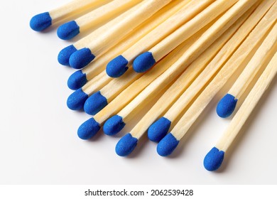 Blue wooden matches on a light gray background. Matchsticks with bright blue heads macro. Scattered wooden matches without box close-up. Design element for smoker accessory concept. Top view.