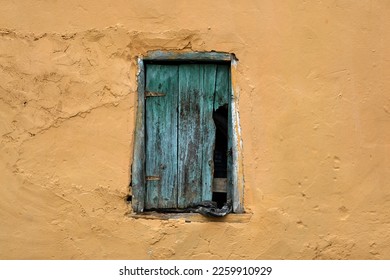 
Blue wooden window detail of a ruined village house with orange walls