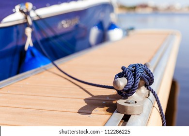 A blue yacht moored with a line tied around a fixing on the quayside/ Mooring at a pier