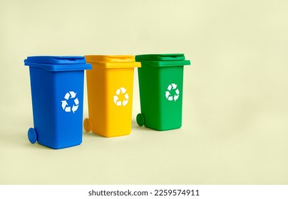 Contenedor azul, amarillo y verde para la recogida de basura separada de plástico, papel y material orgánico, aislado en el fondo amarillo con espacio de copia, concepto de reciclaje de residuos