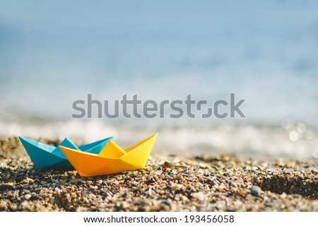 Blue and yellow paper boats on beach outdoors 