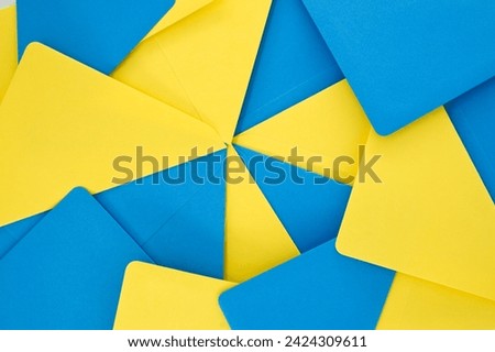 Blue and yellow paper envelopes organized in a symmetrical pattern gives the appearance of a three-dimensional, exploding geometry that adds a sense of depth and vibrancy