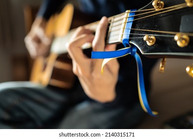 Blue and yellow ribbon for Ukraine tied on a guitar