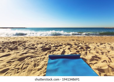 Blue yoga mat is on a sandy beach by the sea. Barcelona, Spain - Powered by Shutterstock