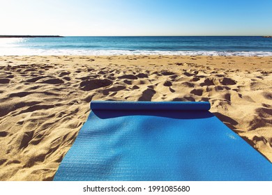 Blue yoga mat is on a sandy beach by the sea. Barcelona, Spain - Powered by Shutterstock