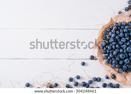Blueberries on the paper on a wooden white background