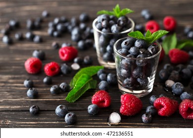 Blueberries, raspberries and mint at black wooden table. Summer organic berry. Agriculture, Gardening, Harvest Concept